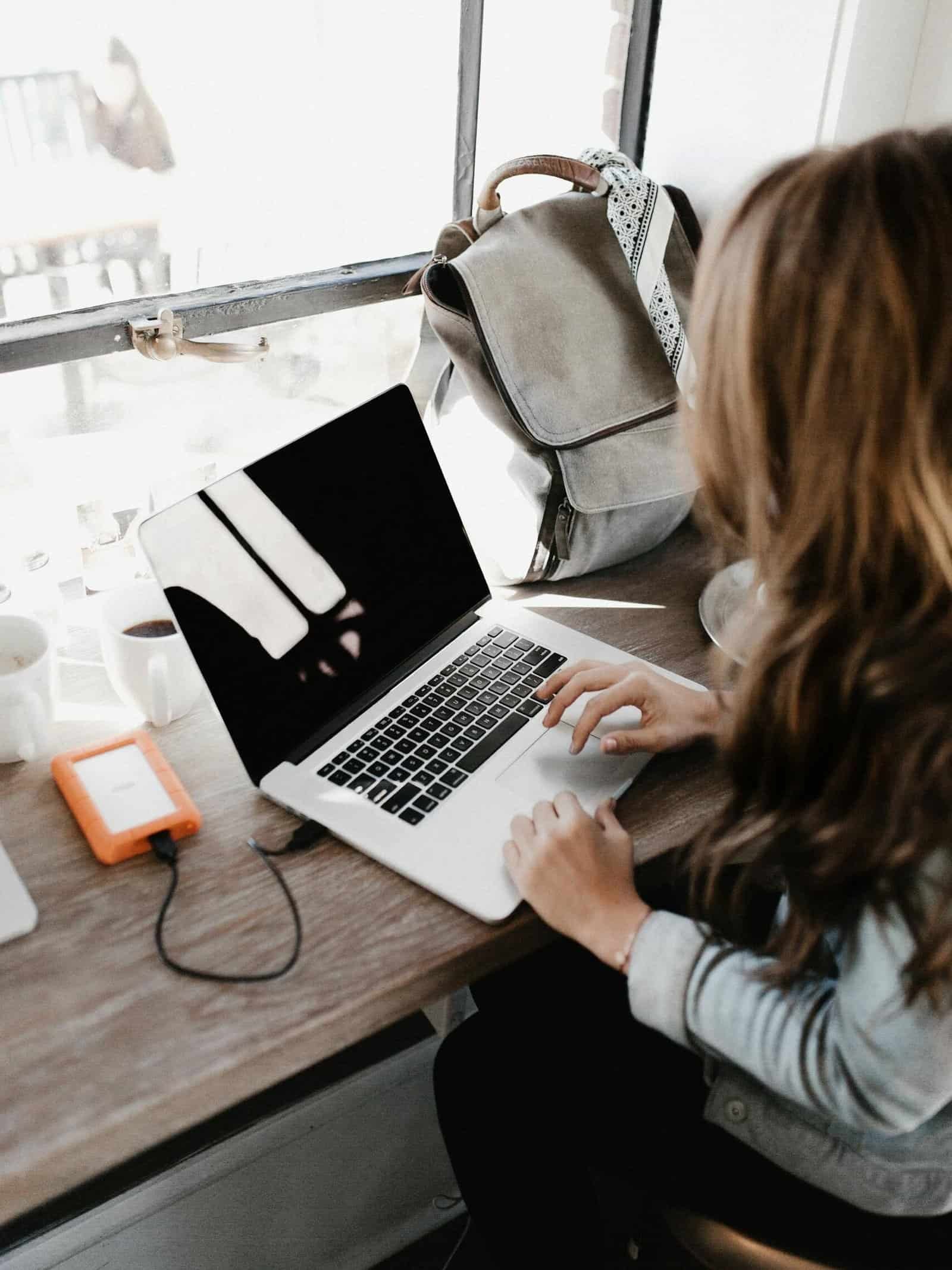 Close-up Photography of Woman Sitting Beside Table While Using Macbook